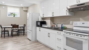 A modern kitchen with white cabinets, a black countertop, and a built-in oven. - Dilalla Residence -The Hidden Vine Retreat (Niagara Falls)