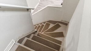 A staircase with a unique geometric design, white walls, and a handrail. - Dilalla Residence -The Hidden Vine Retreat (Niagara Falls)