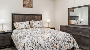 A bedroom with a bed, nightstands, a dresser, a mirror, and a painting on the wall. - Dilalla Residence -The Hidden Vine Retreat (Niagara Falls)