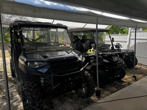 Ett takförsett utomhusområde där två fyrhjulingar står parkerade under ett skydd.
