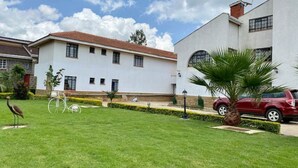 Un edificio con fachada blanca, tejado rojo y un césped cuidado con una palmera.
