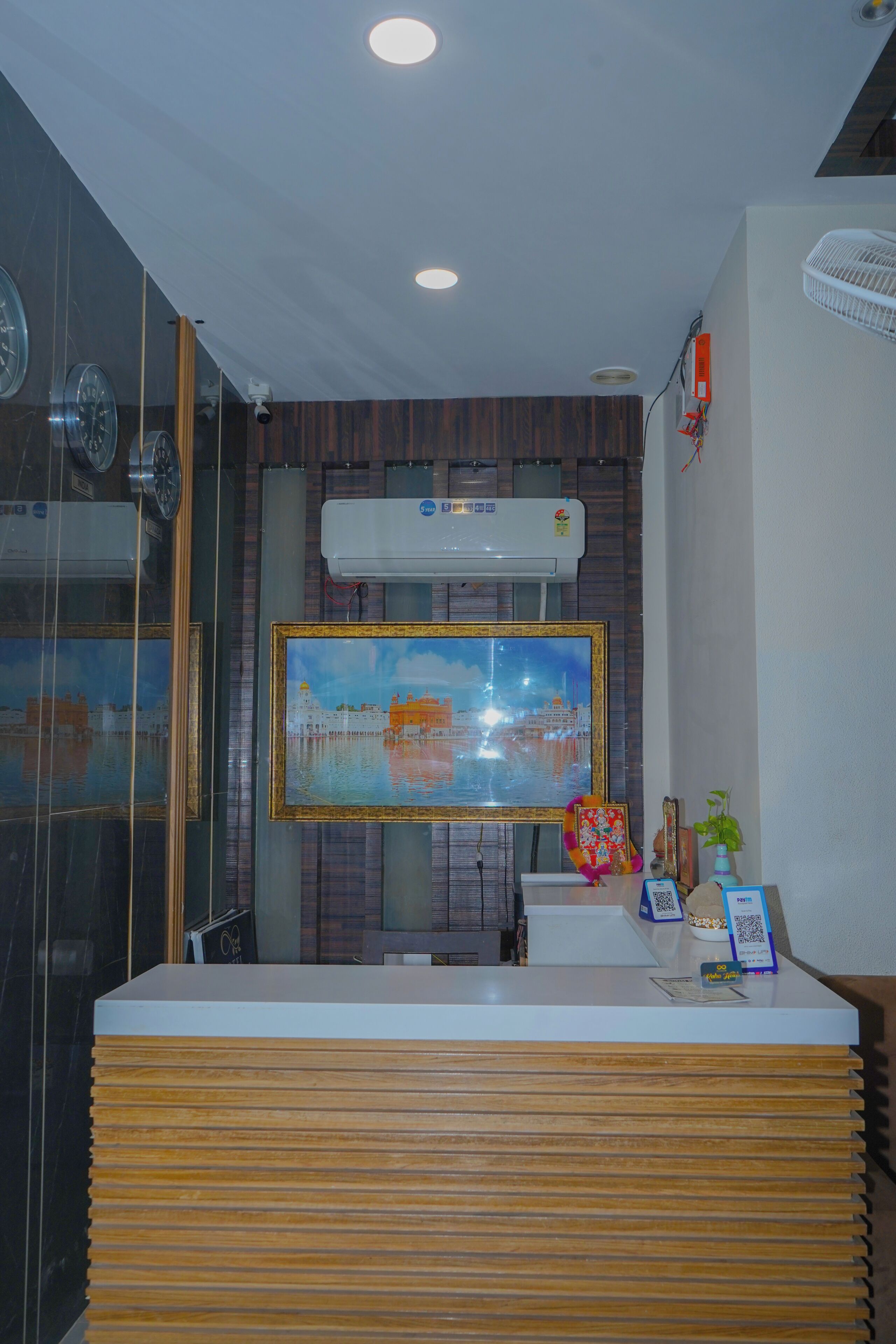 A reception desk with a modern design, a mounted air conditioner, and a framed painting above it.