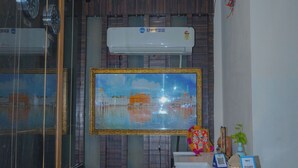 A reception desk with a modern design, a mounted air conditioner, and a framed painting above it. - Infinity Hotel by Kalra Hotels Amritsar (Amritsar)