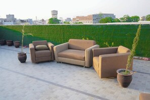 A rooftop terrace with a sofa set, potted plants, and a view of the cityscape. - Infinity Hotel by Kalra Hotels Amritsar (Amritsar)