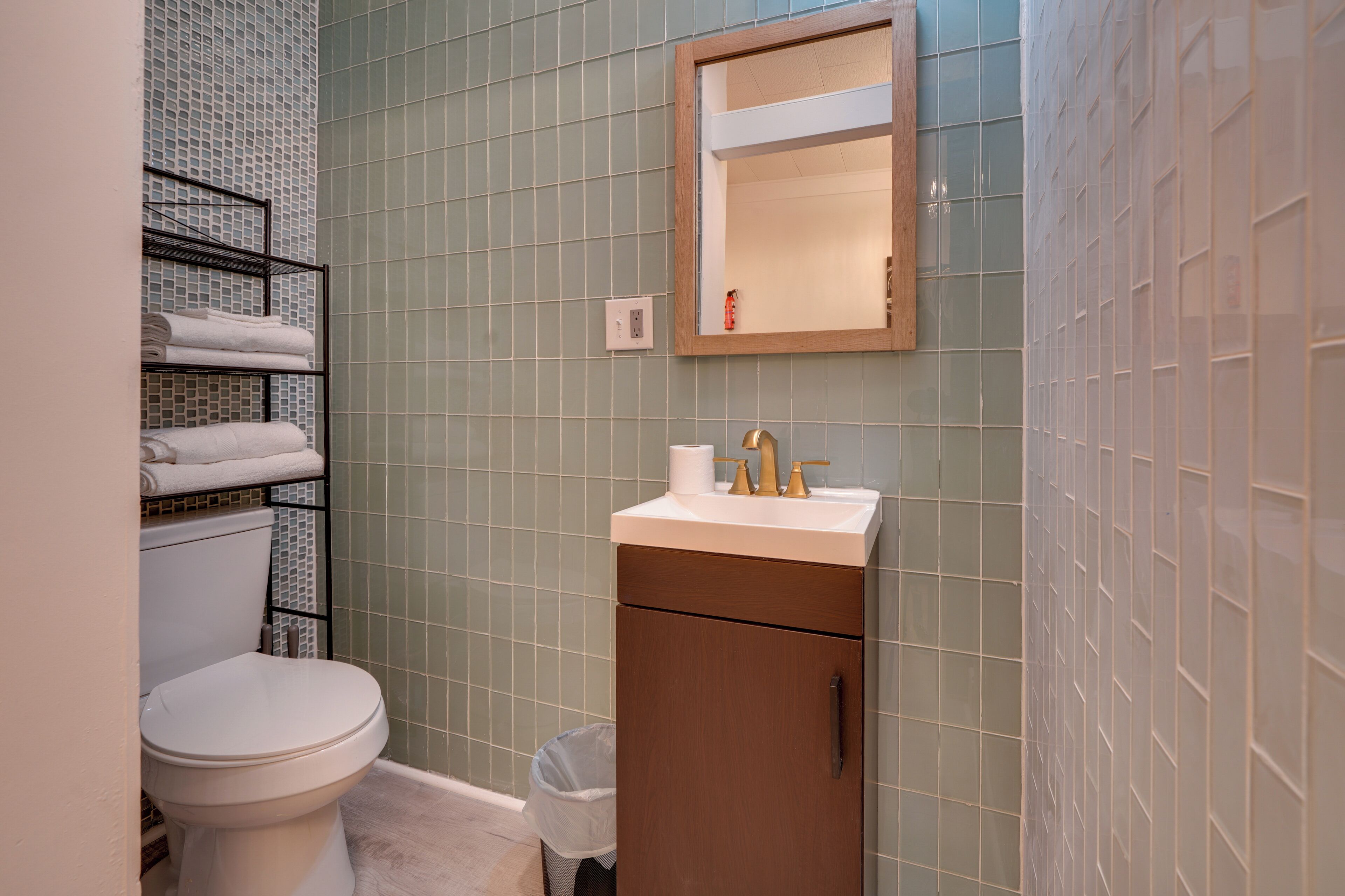 Un baño con inodoro, lavamanos con espejo y toallero.