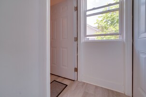 A white door with a window, a doormat, and a light-colored floor.