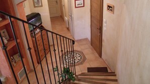 A staircase leading to a landing with a door, a tiled floor, and a small plant. - A quiet house in Haute-Provence with a pool, garden, and large terrace. (La Brillanne)