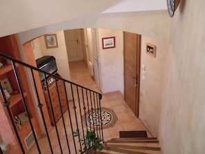 Eine Treppe führt zu einer Zwischenebene mit einer Tür, einem gefliesten Boden und einer kleinen Pflanze.