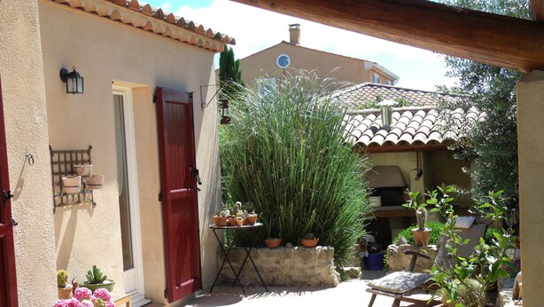 A patio with potted plants, a red door, and a stone wall. - A quiet house in Haute-Provence with a pool, garden, and large terrace. (La Brillanne)