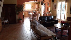 A spacious living room with a sofa, a dining area, and a kitchen visible in the background. - A quiet house in Haute-Provence with a pool, garden, and large terrace. (La Brillanne)