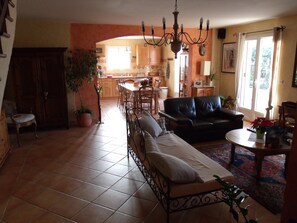 Ein geräumiges Wohnzimmer mit einer Couch, einem Essbereich und einer im Hintergrund erkennbaren Küche.