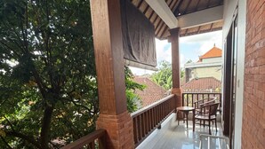 A covered balcony with a tiled floor, wooden railings, and a view of a house with a red roof. - Room-a Quiet Room With Balcony in the he (Ubud)