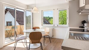 Una cocina moderna con comedor, ventanas amplias y vistas a una casa.