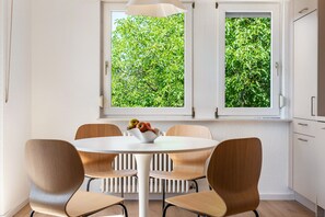 A dining area with a round table, four chairs, and a bowl of fruit. - Reichenau Apartment in Salem (Salem)