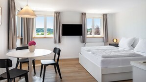 Ein Hotelzimmer mit Bett, Schreibtisch, Stuhl, Fernseher und einem Fenster mit Vorhängen.