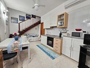 A kitchen with a microwave, oven, and wooden cabinets. - Central vacation home that sleeps 6, just 5 meters from crystal-clear beaches (Sardegna)