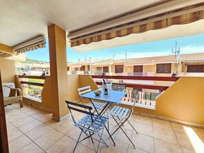 A balcony with a table, chairs, and a view of neighboring buildings. - Central vacation home that sleeps 6, just 5 meters from crystal-clear beaches (Sardegna)