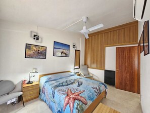 A bedroom with a bed, a desk, a chair, a wardrobe, a ceiling fan, and two framed pictures on the wall. - Central vacation home that sleeps 6, just 5 meters from crystal-clear beaches (Sardegna)