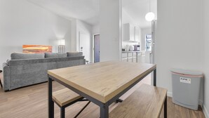 Una sala de estar moderna con una mesa de madera, sofá gris y un cesto de basura.