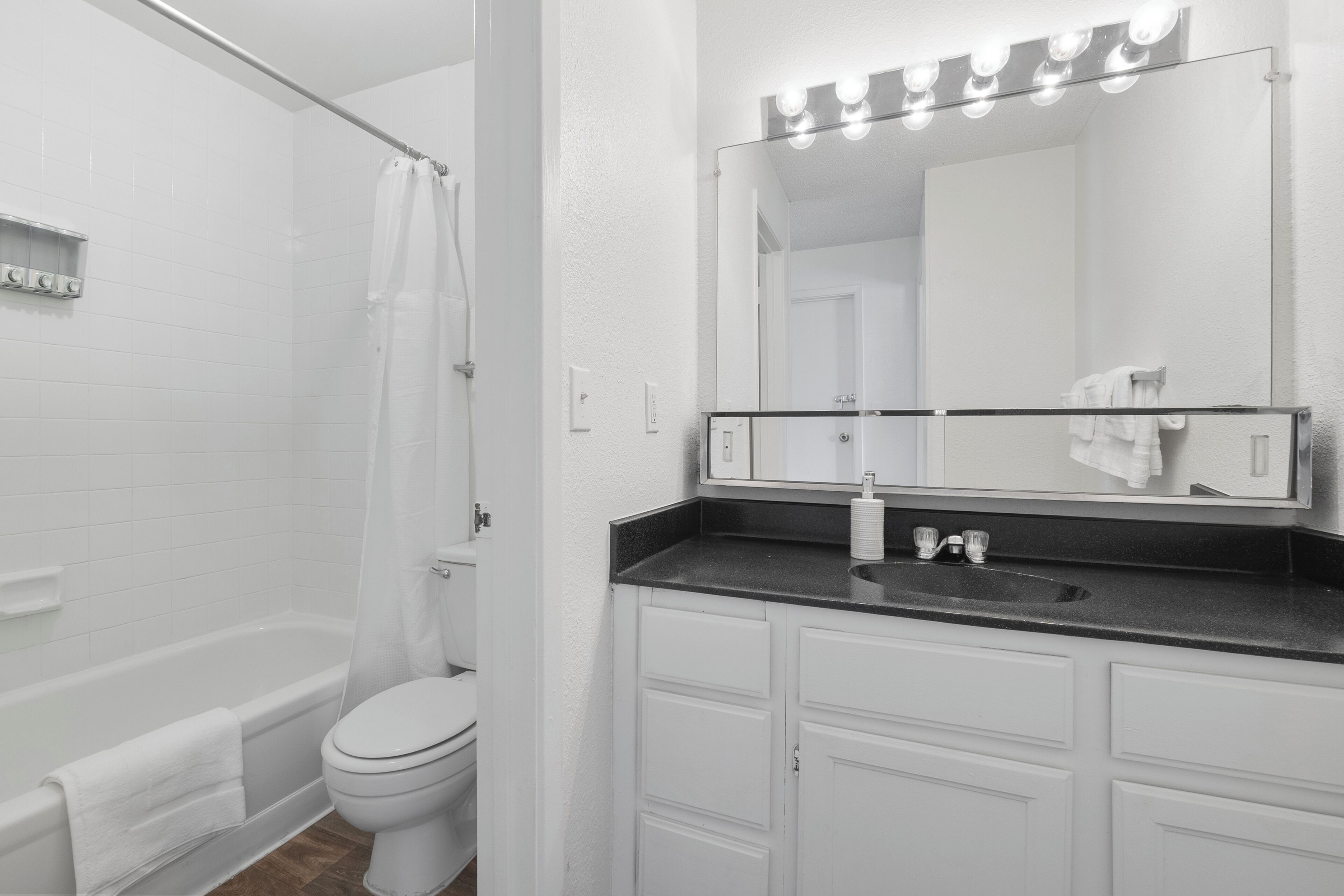 Un baño con bañera, inodoro, tocador con espejo y lavabo.