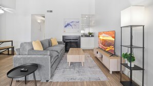 Una sala de estar moderna con sofá, mesa de centro, televisor, chimenea y estanterías.