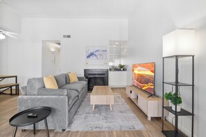 Una sala de estar moderna con sofá, mesa de centro, televisor, chimenea y estanterías.
