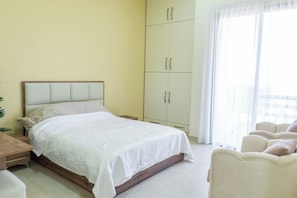 Ein Schlafzimmer mit Bett, Kleiderschrank, Schreibtisch und Stuhl.