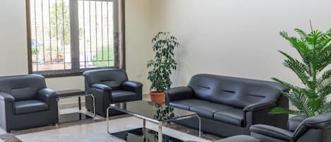 A modern lobby with a sofa set, a coffee table, and potted plants.
