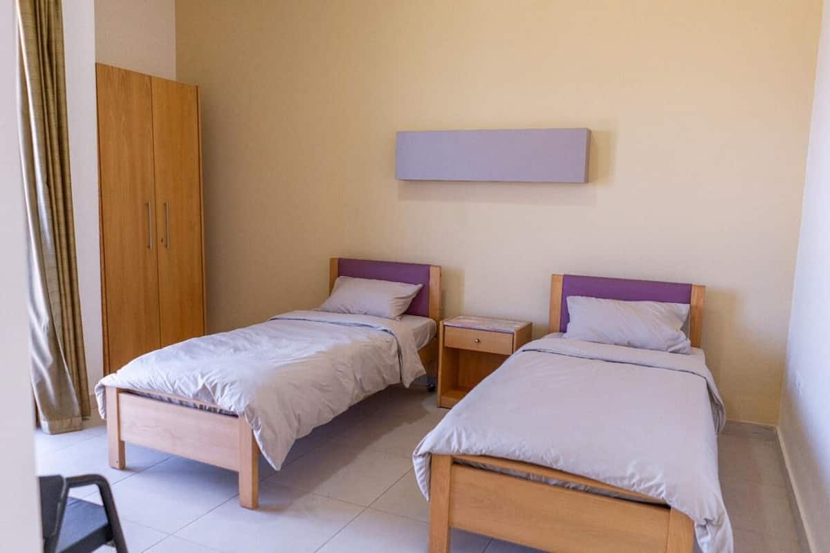 Ein Zimmer mit zwei Betten, einem Schrank und einem Nachttisch.