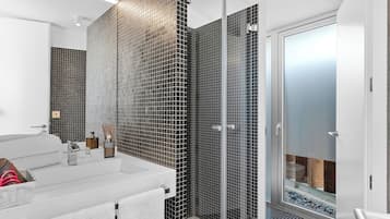 A modern bathroom with a glass shower enclosure, a white sink, and a mirror.