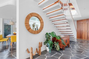 Un intérieur moderne agrémenté d’un escalier en colimaçon, d’un miroir rond et d’une décoration à base de cactus.