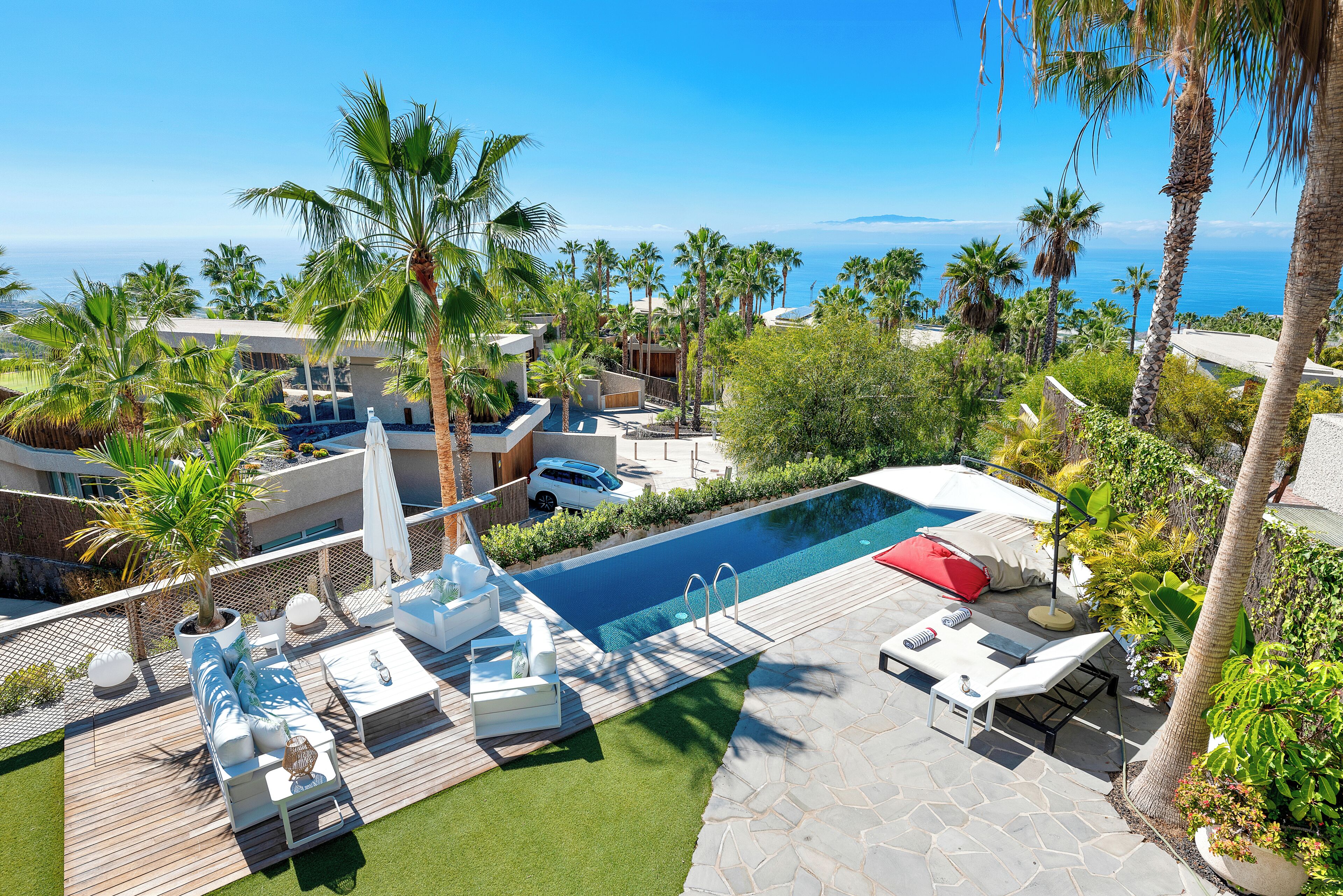 Un espace piscine avec des chaises longues et vue sur l’océan.