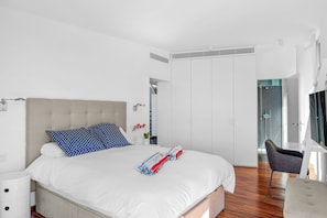 Une chambre moderne avec un grand lit, une table de chevet, une chaise et un dressing.