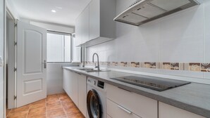 Una cocina compacta con lavadora, un lavamanos y una ventana.