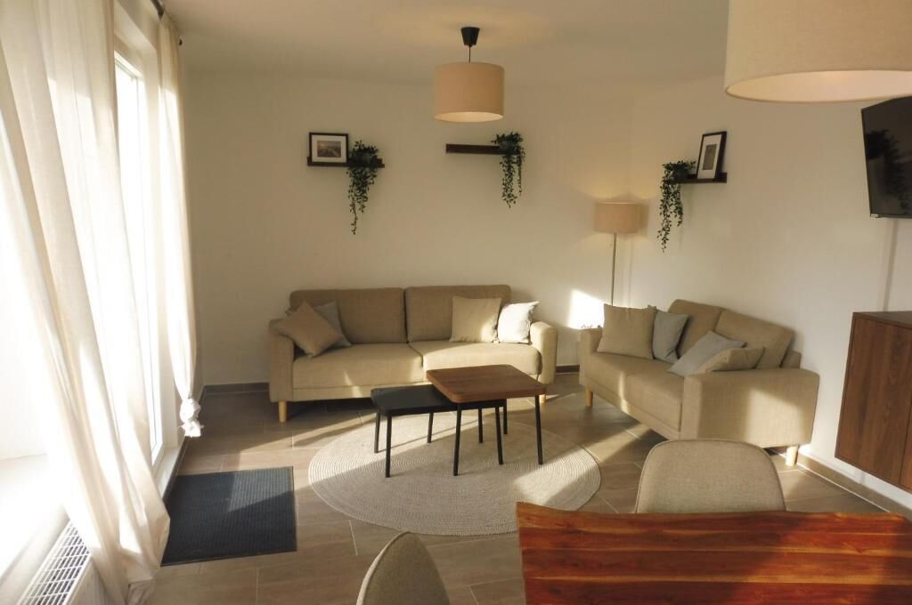 Uma sala de estar com dois sofás, uma mesa de centro e um abajur.
