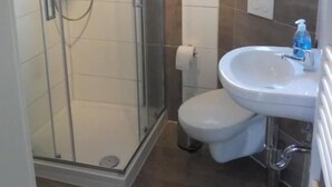 Um banheiro com box de vidro, pia branca e vaso sanitário.