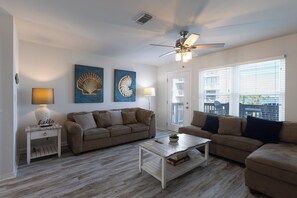 A living room with two sofas, a coffee table, a lamp, and two wall art pieces. - CNB10- West Beach Jewel! Amazing View! Enjoy The Beach & Lagoon! (Gulf Shores)