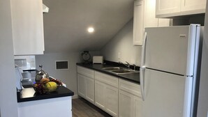 A modern kitchen with white cabinetry, a stainless steel refrigerator, a sink, and a microwave. - Charming 3-bedroom house in adorable Bodden Town with AC (Bodden Town)