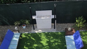 A patio with two lounge chairs, a small table, and a white barbecue grill. - Charming 3-bedroom house in adorable Bodden Town with AC (Bodden Town)