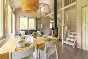 Un comedor con una mesa de madera dispuesta para cuatro personas, una escalera y vistas al exterior.
