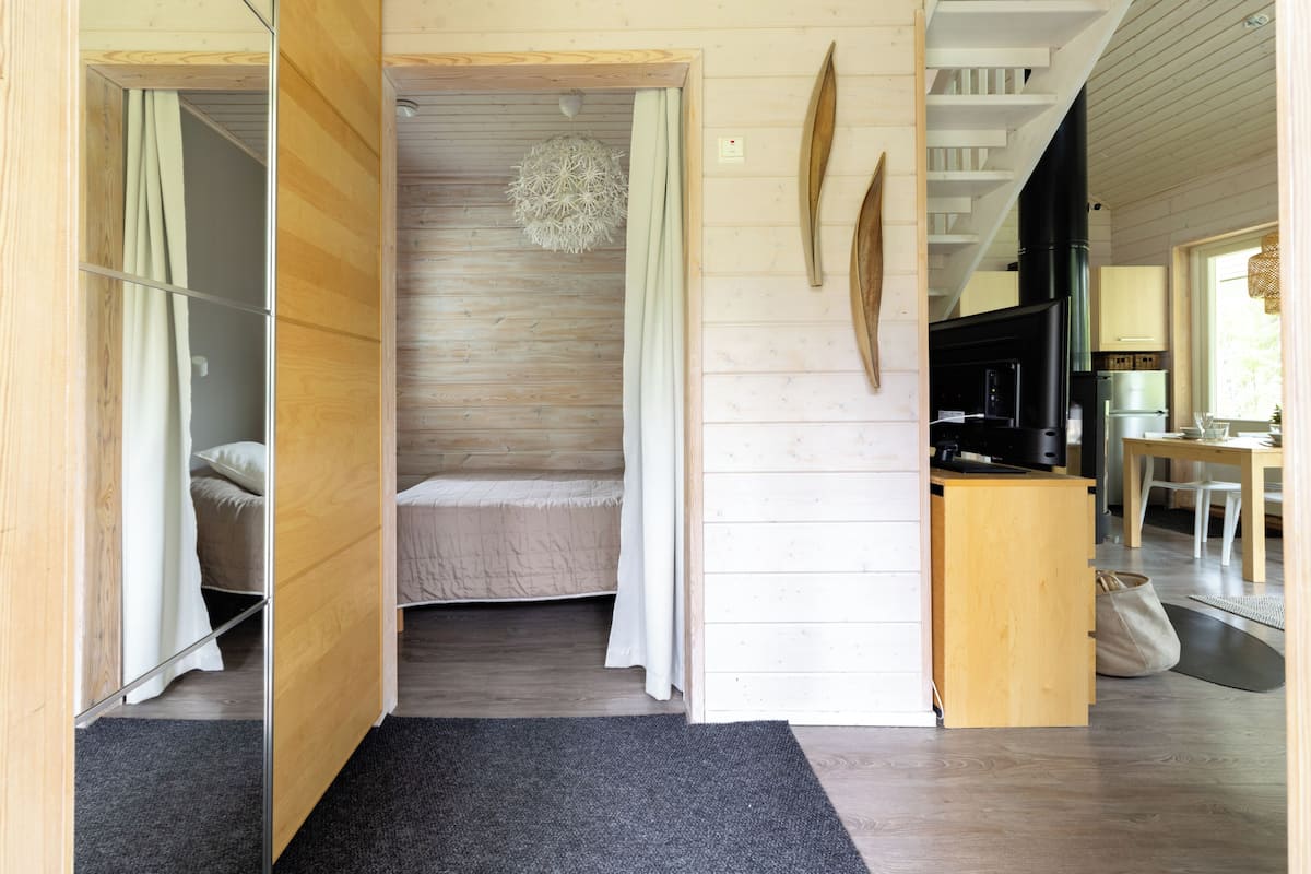 A wooden interior with a bed, a small kitchenette, and a dining area.