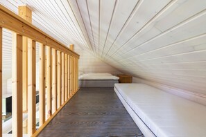 Un dormitorio abuhardinado con piso de madera, un colchón y techo inclinado.