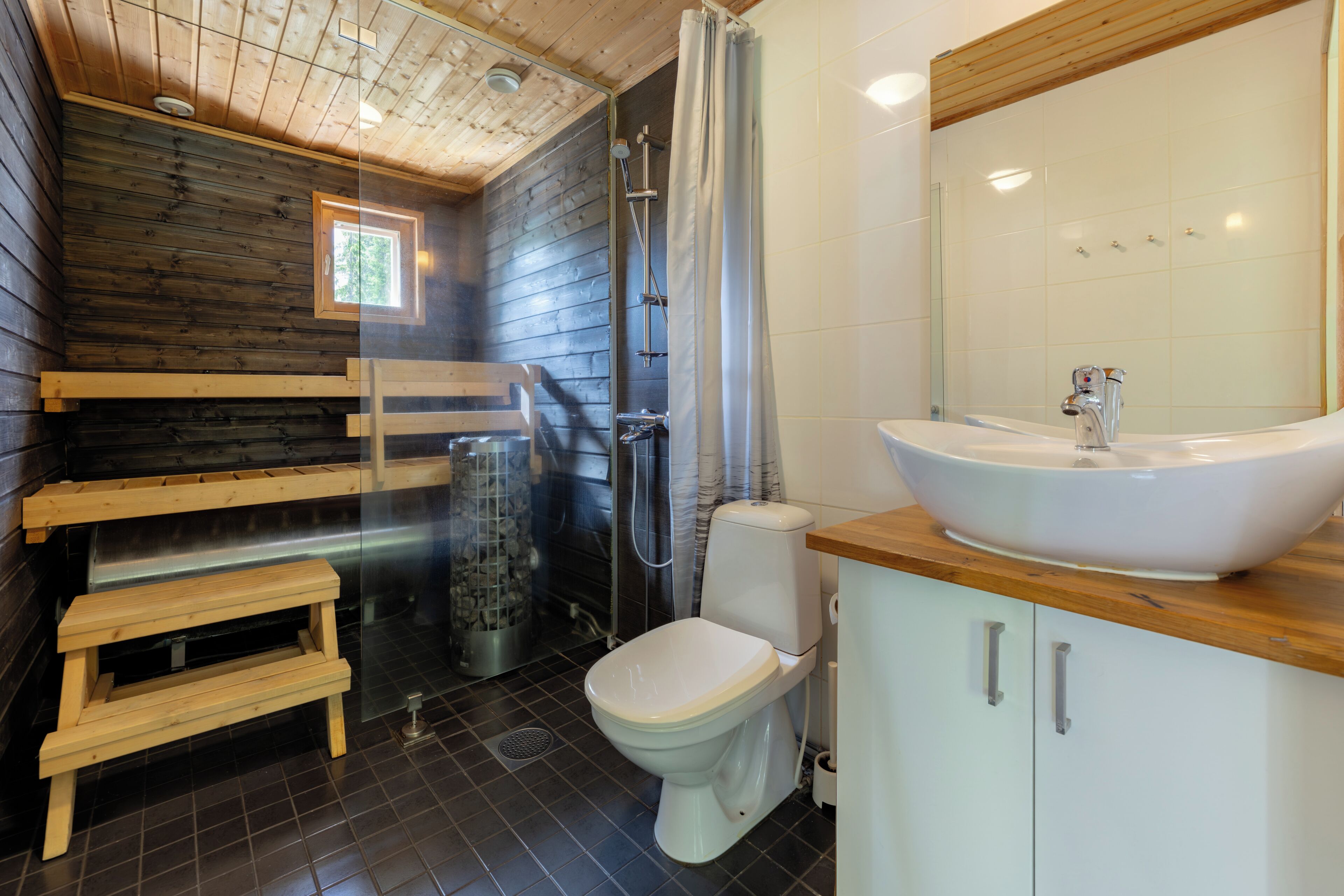 A bathroom with a wooden bench, a white sink, and a shower area.