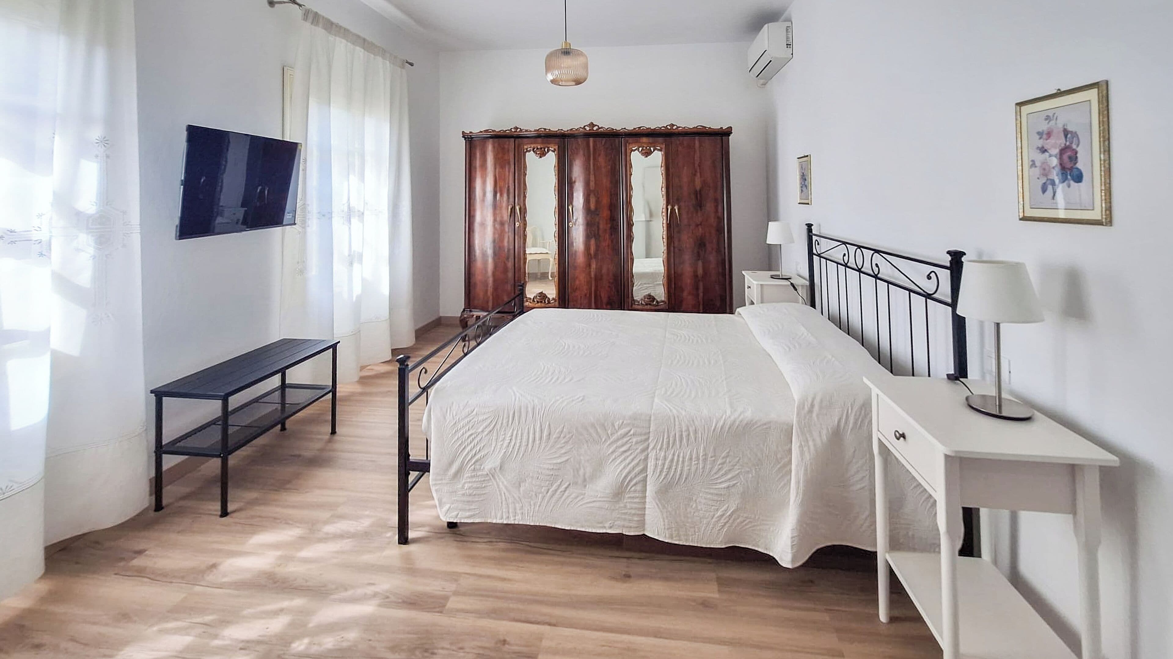 Une chambre à coucher avec un lit, une table de chevet, une lampe et un téléviseur fixé au mur.
