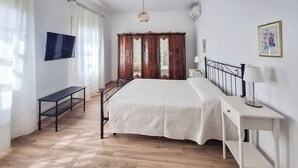 Ein Schlafzimmer mit Bett, Nachttisch, Lampe und Fernseher an der Wand.
