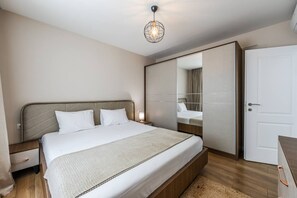 Ein Schlafzimmer mit Bett, Nachttisch, Lampe, Kleiderschrank und einer Pendelleuchte.