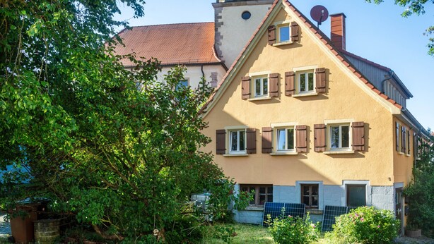 A two-story house with a sloped roof, a chimney, and a satellite dish. - Apartment 'Alte Schmiede Ellrichshausen' with Wi-Fi (Satteldorf)