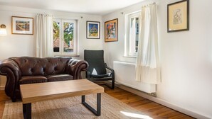 A living room with a brown leather sofa, a black chair, a wooden coffee table, and a radiator. - Apartment 'Alte Schmiede Ellrichshausen' with Wi-Fi (Satteldorf)
