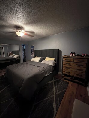Ein Schlafzimmer mit Bett, Schminktisch und Deckenventilator.