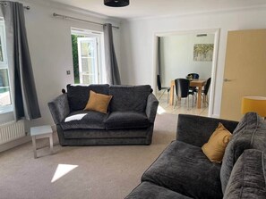 Ein Wohnzimmer mit einer Couch, einem Couchtisch und einem Essbereich mit Stühlen und einem Tisch.